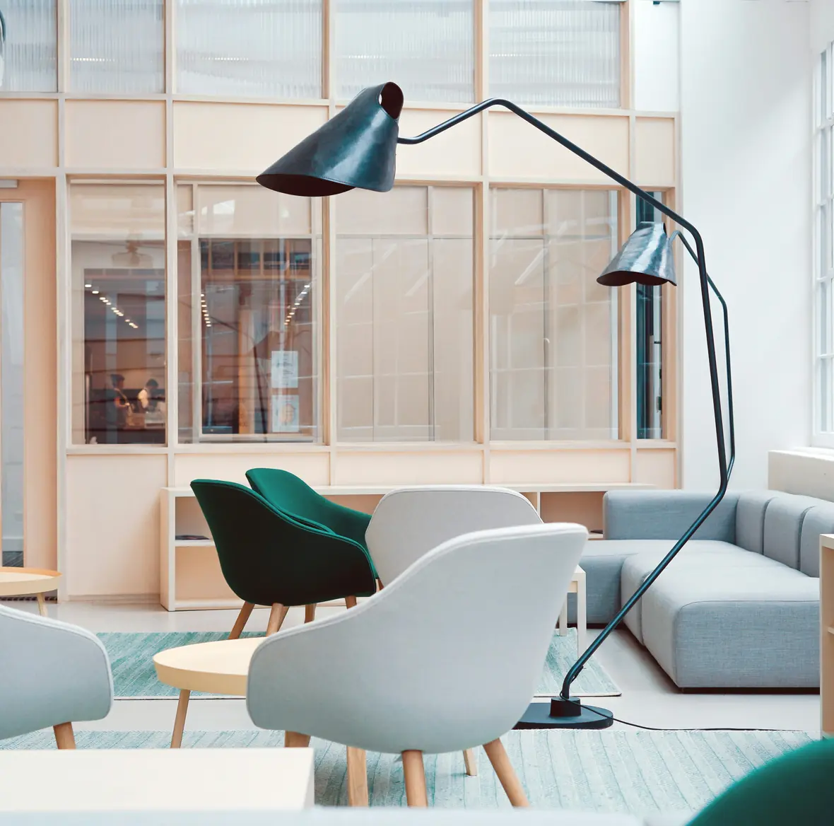 A bright, modern office lounge with soft seating and a floor lamp